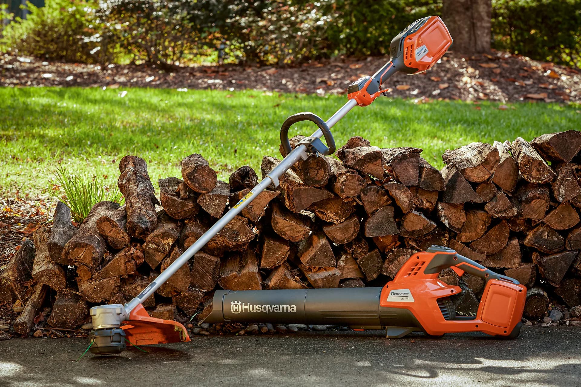 Husqvarna garden equipment in front of a woodpile