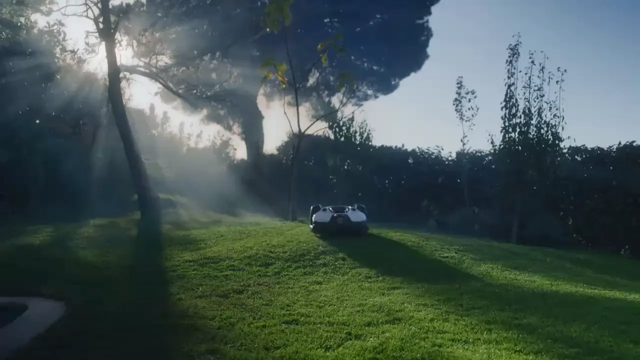Husqvarna robotic mower on a sunny lawn, sunbeams falling through the trees