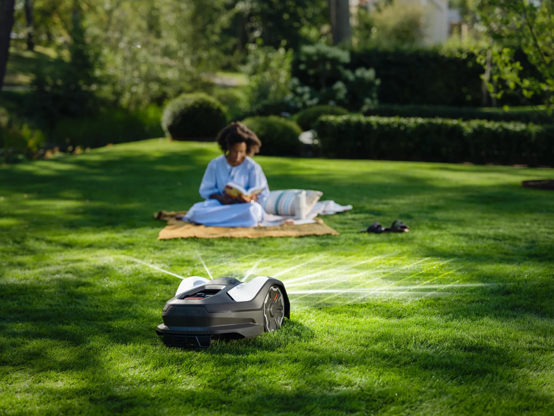 A watered lawn with a robotic mower in front of a house